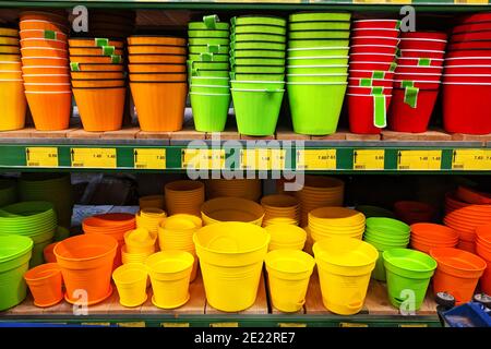 Vasi di fiori sono venduti al deposito. File di pentole colorate diverse per piante da interno su scaffali in un supermercato. Foto Stock