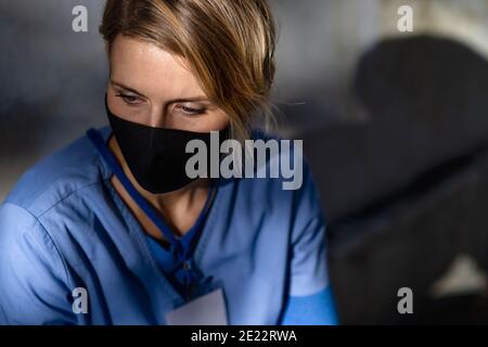 Donna stanca che si prende cura di lei, infermiera o operatore sanitario seduto all'aperto sulla strada per lavorare. Foto Stock
