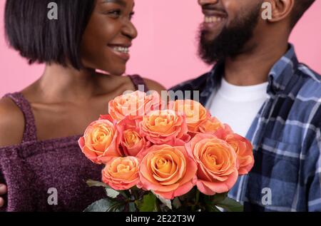 Coppia di innamorati che tengono bel bouquet di rose per San Valentino su sfondo rosa studio, fuoco selettivo Foto Stock