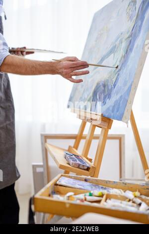 artista che applica vernice su tela con pennello, la sua mente piena di immaginazione, pittore creativo durante il lavoro Foto Stock