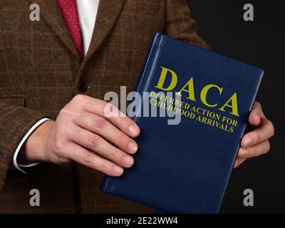 Azione differita per Arrivi Infanzia DACA Concept. L'uomo in abito mostra il libro. Foto Stock