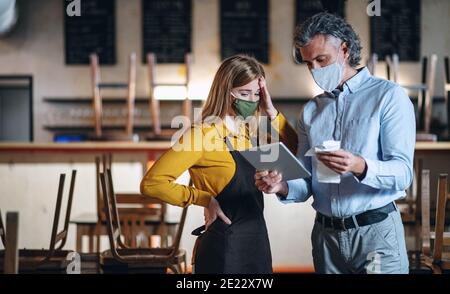 Il proprietario è stato frustrato con una cameriera in un caffè chiuso, un piccolo blocco per affari a causa del coronavirus. Foto Stock