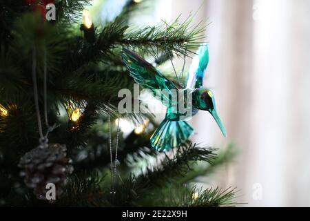 Un 'cristallo' hummingbird decorazione albero di Natale (bauble) in riflessi verdi scintille, su un albero di Natale. Il colibrì è un simbolo della demenza della PSP Foto Stock