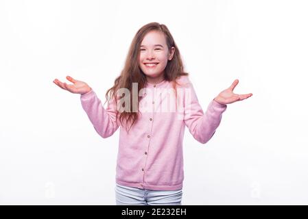 La ragazza sorridente sta tenendo le braccia in su gesturing come doesnt sa o che cosa sopra sfondo bianco. Foto Stock