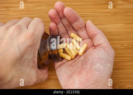 Persona che prende le pillole del complesso della vitamina B da una bottiglia. Primo piano. Foto Stock