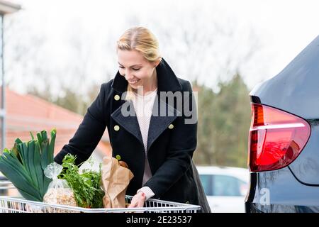 Donna che carica i generi alimentari dopo lo shopping nel tronco della sua auto Foto Stock