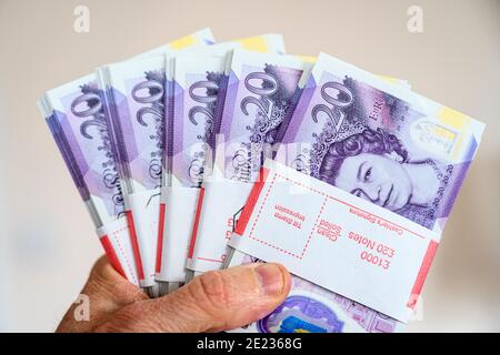 Primo piano della mano che tiene £5000 contanti in 20 £banconote. Valuta britannica. Sterlina britannica. Foto Stock