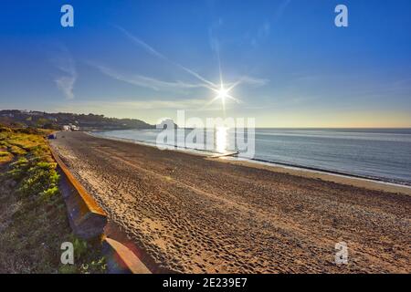 Immagine della baia di Grouville con il castello di Gorey sullo sfondo con un mare liscio all'alba con la spiaggia e il cielo blu. Jersey, Isole del canale, Regno Unito Foto Stock