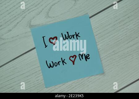 I Love Work and Work Love Me scrive su note appiccicose isolate su tavola di legno. Foto Stock