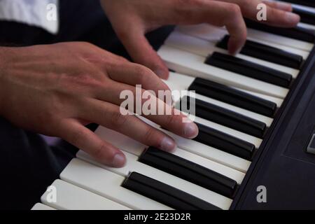 Primo piano di mani di musicista maschile che suonano su un pianoforte elettronico tastiera in studio Foto Stock