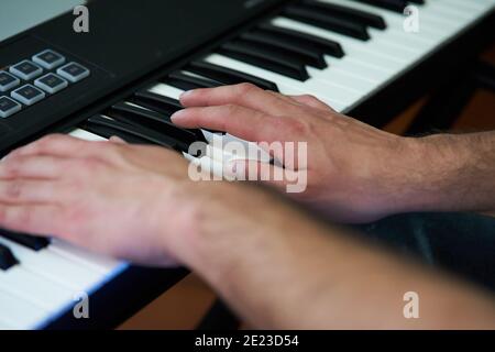 Primo piano di mani di musicista maschile che suonano su un pianoforte elettronico tastiera in studio Foto Stock