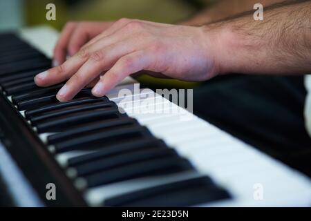 Primo piano di mani di musicista maschile che suonano su un pianoforte elettronico tastiera in studio Foto Stock