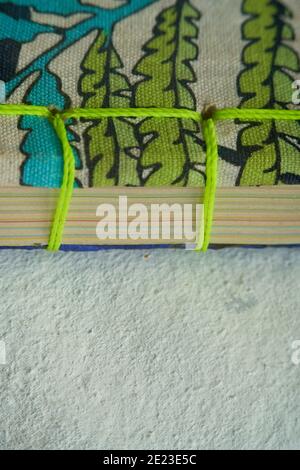 Primo piano dei fogli di carta piegati rilegati con filo verde Foto Stock