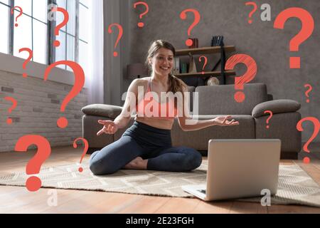 La giovane donna segue gli esercizi di palestra con un computer portatile ma sha ha alcune domande Foto Stock