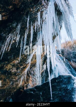 Formazioni di ghiaccio. Cascata ghiacciata. Formazione di ghiaccio da una cascata ghiacciata sopra una grotta. Acqua congelata, vista della chiocida. Carta da parati di inverno, freddo e gelo Foto Stock