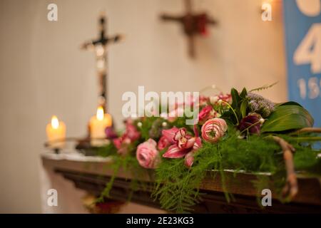 Interno di una Chiesa cattolica romana con decorazione policromo dell'altare e dei fiori, con una croce fuori fuoco con Gesù Cristo sullo sfondo. Foto di alta qualità Foto Stock