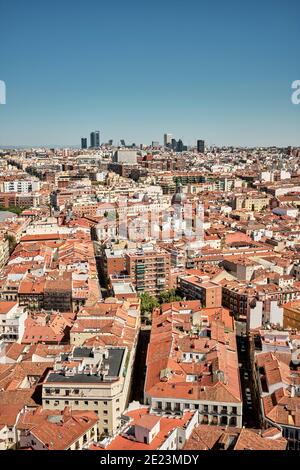 Dall'alto di un vecchio edificio residenziale con tetti di tegole rosse Situato nel quartiere di Madrid contro il cielo blu senza nuvole Foto Stock