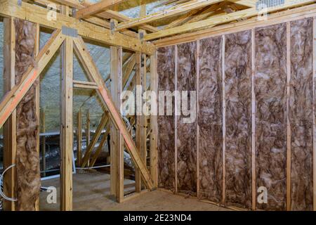 Materiale isolante barriera a freddo in fibra di vetro nella mansarda inclinata di una nuova casa con telaio Foto Stock