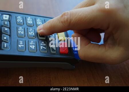 Primo piano della mano di un maschio che inserisce il codice pin per Una carta di credito sul terminale POS Foto Stock