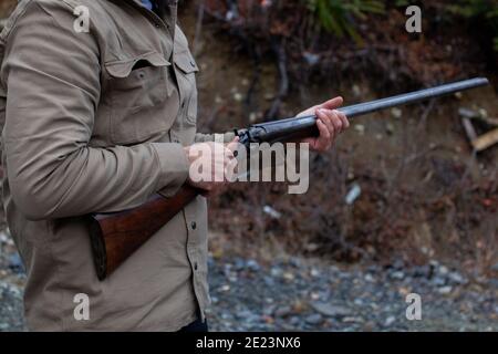 Un uomo tiene un vecchio, antico, fucile a doppio cilindro alla sua vita, indicando il barile downrange, pronto per il caricamento. Campo di azione all'aperto a Squamish, British-Colu Foto Stock