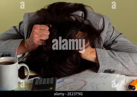 Una donna caucasica stressata sta strappando i capelli mentre lavora su una panchina su un incarico. Ci sono un sacco di note, carte e una tazza di caffè su des Foto Stock