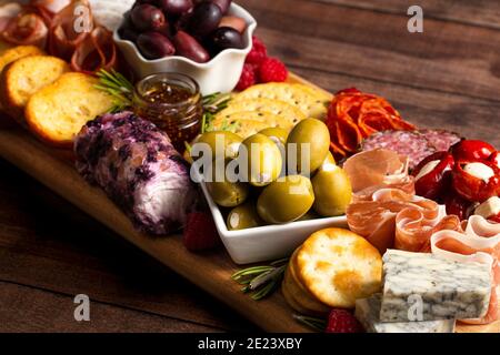 Salato Charcuterie Board coperto di carni Olives Peppers Berries e. Formaggio Foto Stock