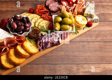 Salato Charcuterie Board coperto di carni Olives Peppers Berries e. Formaggio Foto Stock