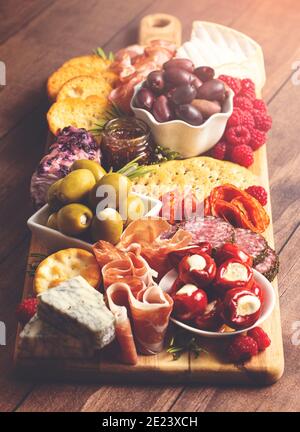 Salato Charcuterie Board coperto di carni Olives Peppers Berries e. Formaggio Foto Stock