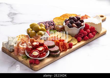 Salato Charcuterie Board coperto di carni Olives Peppers Berries e. Formaggio Foto Stock