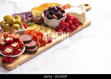 Salato Charcuterie Board coperto di carni Olives Peppers Berries e. Formaggio Foto Stock