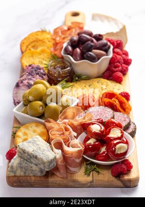 Salato Charcuterie Board coperto di carni Olives Peppers Berries e. Formaggio Foto Stock