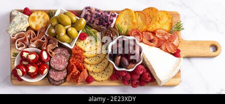 Salato Charcuterie Board coperto di carni Olives Peppers Berries e. Formaggio Foto Stock