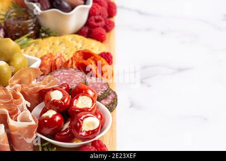 Salato Charcuterie Board coperto di carni Olives Peppers Berries e. Formaggio Foto Stock