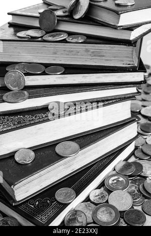 Mucchio di libri circondato da molte monete diverse [Nero e. Versione bianca] Foto Stock