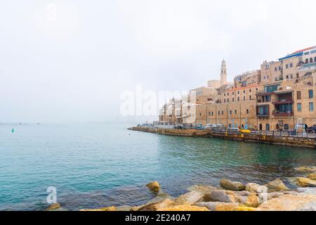 Old Jaffa Port e Tel-Aviv in tempo di nebbia. Antiche case in pietra che si affacciano sul Mar Mediterraneo. Foto di alta qualità Foto Stock