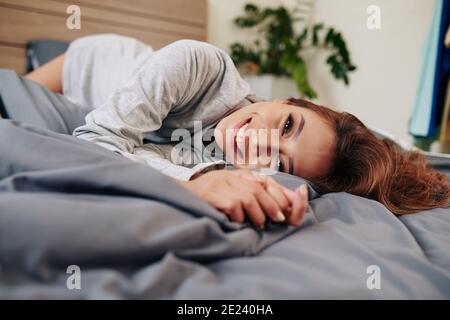 Donna che si rilassa sul comodo letto Foto Stock