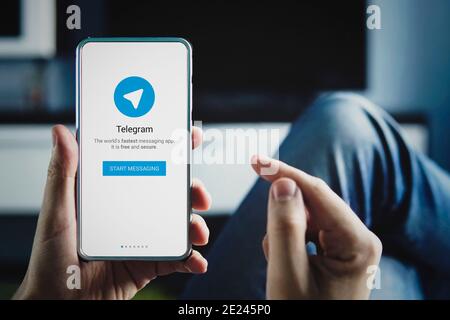 Uomo che tiene lo smartphone con il logo Telegram con il dito sullo schermo a casa. 22 luglio 2018. Barnaul, Russia. Foto Stock