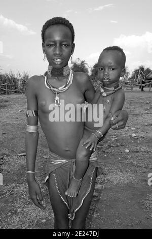 Ragazza giovane di tribe di Hamer che tiene il fratello Foto Stock