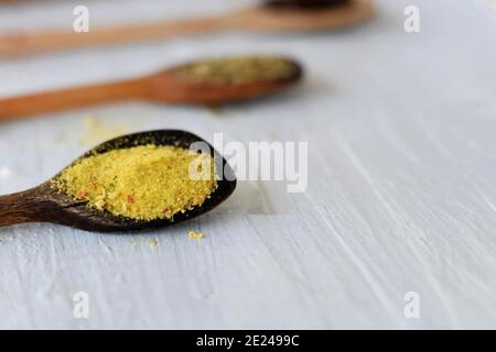 Selezione di erbe e spezie in cucchiai di legno su sfondo di legno. Foto Stock