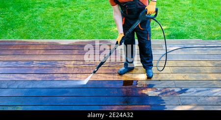 lavaggio elettrico - terrazzo per la pulizia dei lavoratori con lavapiatti - pulitore ad alta pressione dell'acqua su superficie in legno Foto Stock