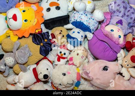 diversi tipi di peluche morbidi giocattoli sul pavimento ovunque in una camera per bambini Foto Stock