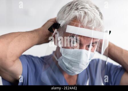 Medico che mette lo schermo di faccia sopra Foto Stock