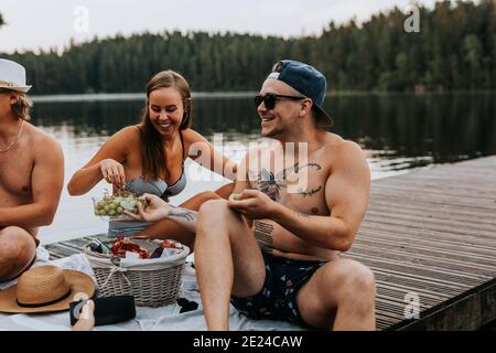 Amici felici che hanno pic-nic sul molo Foto Stock