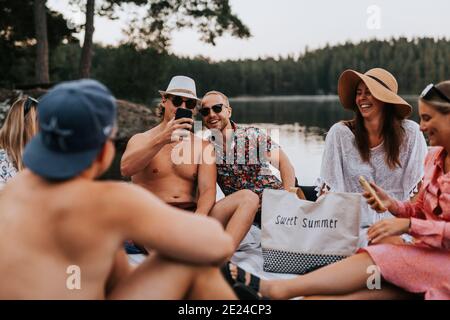 Amici felici che si rilassano sul lago Foto Stock