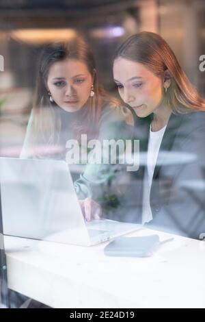 Le donne che usano il computer portatile al bar Foto Stock