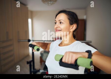 Donna sorridente che lavora con i pesi delle mani Foto Stock