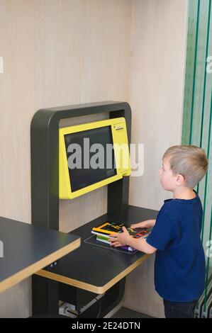 Ragazzo che usa un punto self-service nella libreria Foto Stock