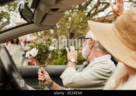 Uomo che agitava mentre si siede in un'auto convertibile Foto Stock