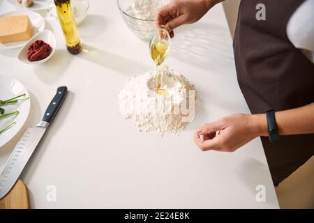 Chef aggiungendo olio d'oliva mentre si prepara l'impasto Foto Stock