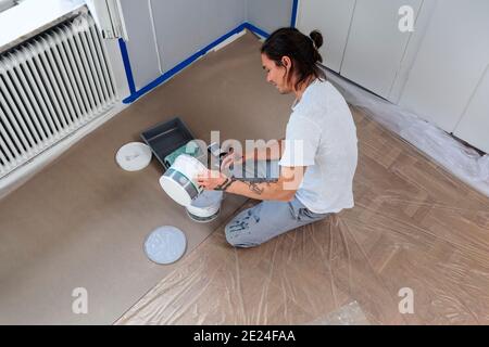 Uomo che prepara la vernice per la pittura della parete Foto Stock